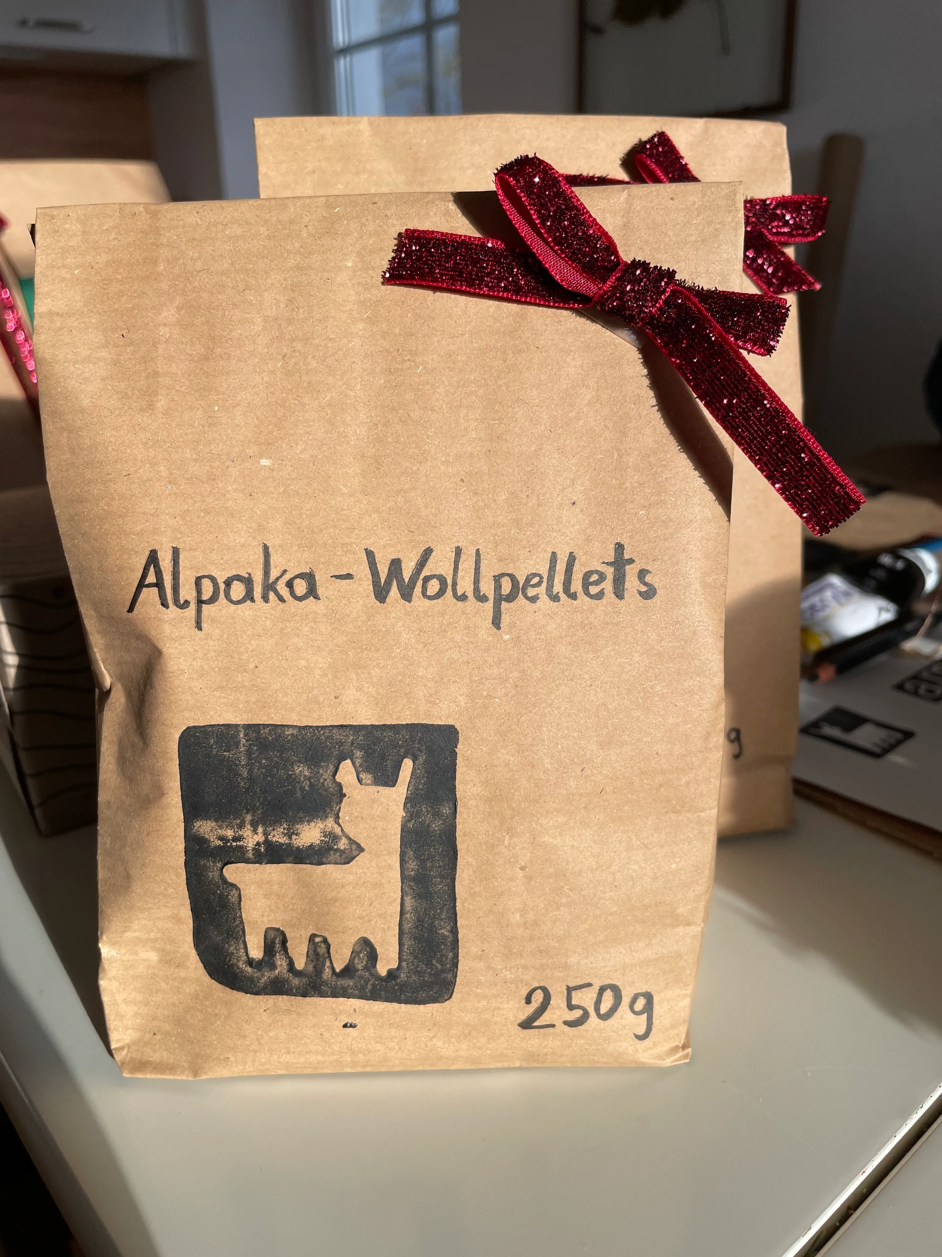 Kraftpapiersackerl mit handgeschriebenem "Alpaka-Wollpellets", Alpaka-Stempel, 250 g und dunkelroter Schleife